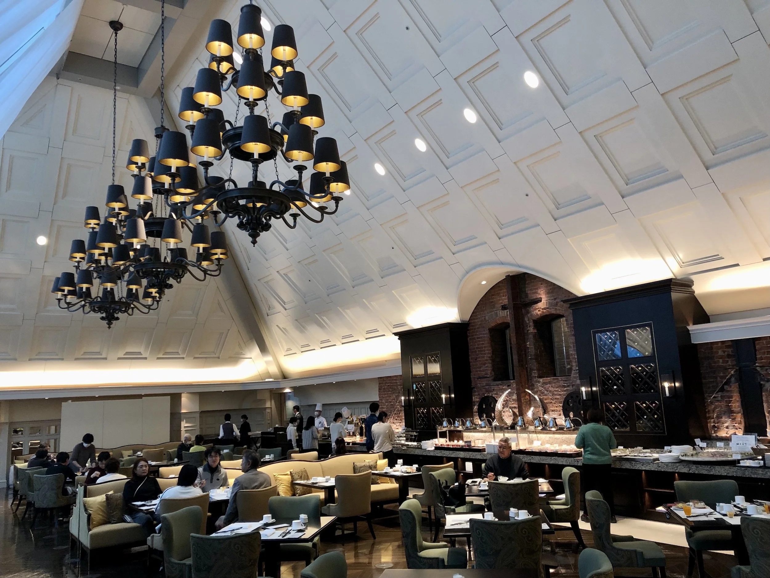 Grand hotel dining hall with tiered black chandeliers and vaulted ceiling