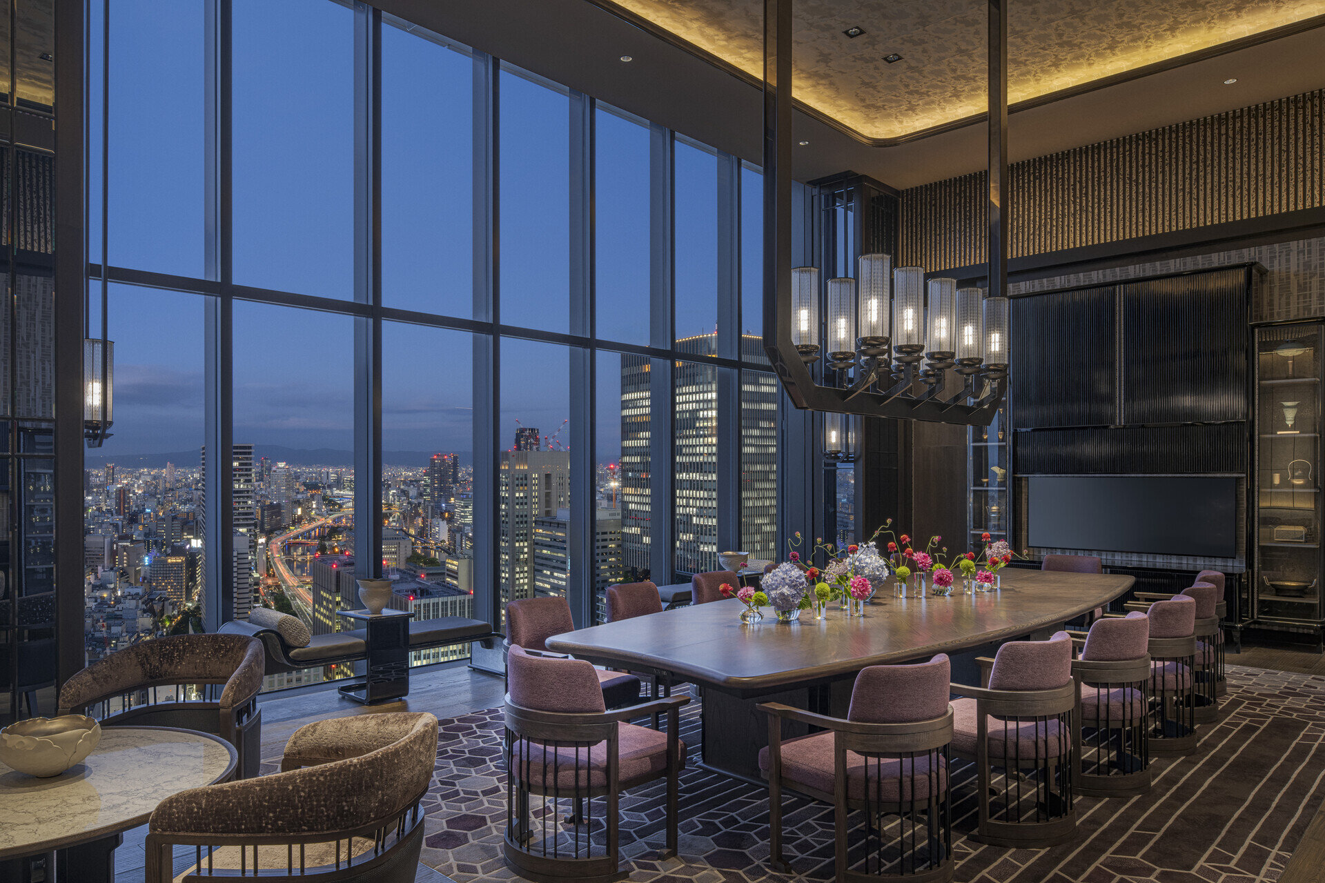 Private dining room with linear pendant chandelier and city skyline view